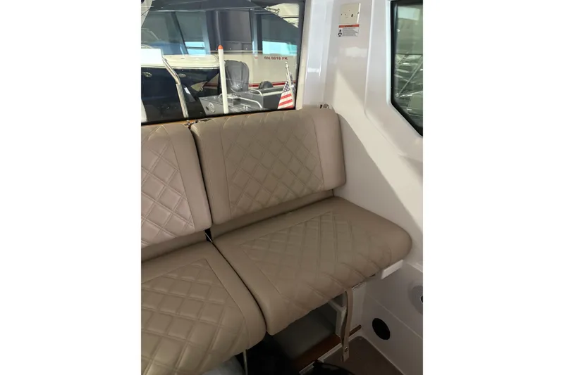 Slide: The Image of 2022 Axopar 28 CABIN interior with quilted beige seating and window view. - 33