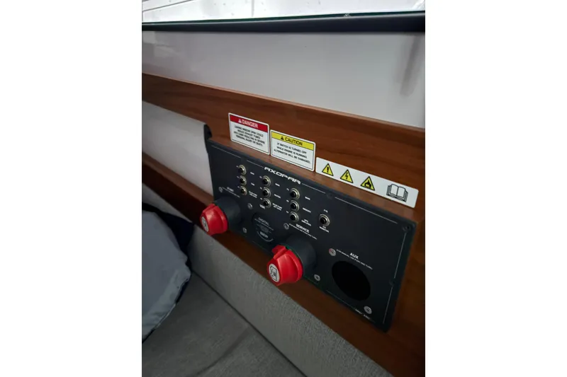 Slide: The Image of Control panel of 2022 Axopar 28 CABIN boat with warning labels and switches. - 34