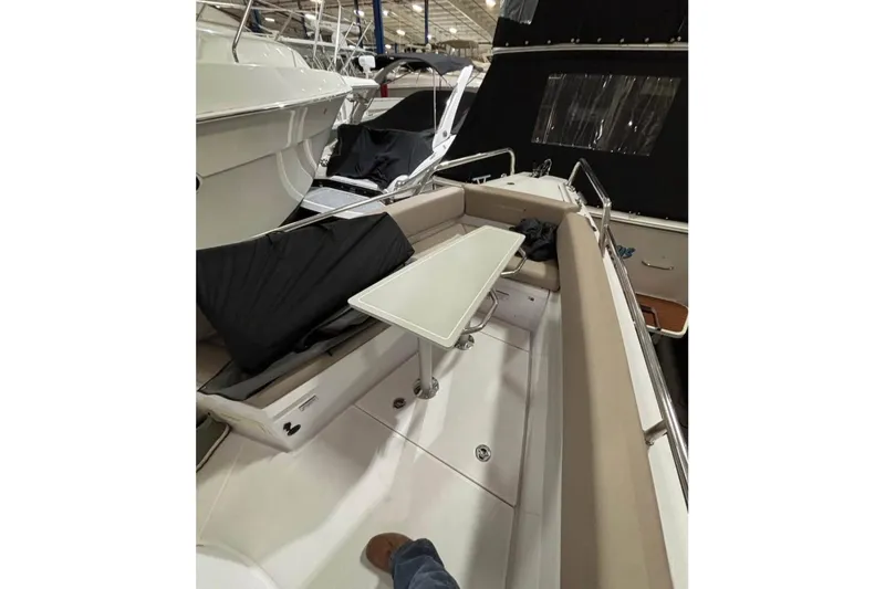 Slide: The Image of 2022 Axopar 28 CABIN boat interior with seating and table in a showroom. - 6