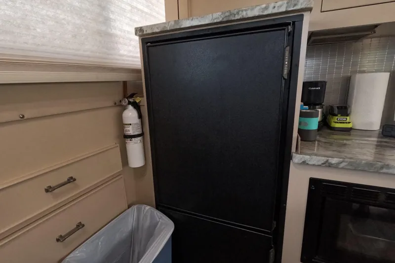 Slide: The Image of 1985 Chris-Craft 381 Catalina interior with black fridge, fire extinguisher, and countertop appliances. - 47