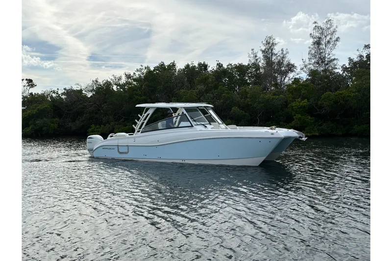 The Image of 2026 World Cat 325 DC boat cruising on calm water near lush greenery. - 0