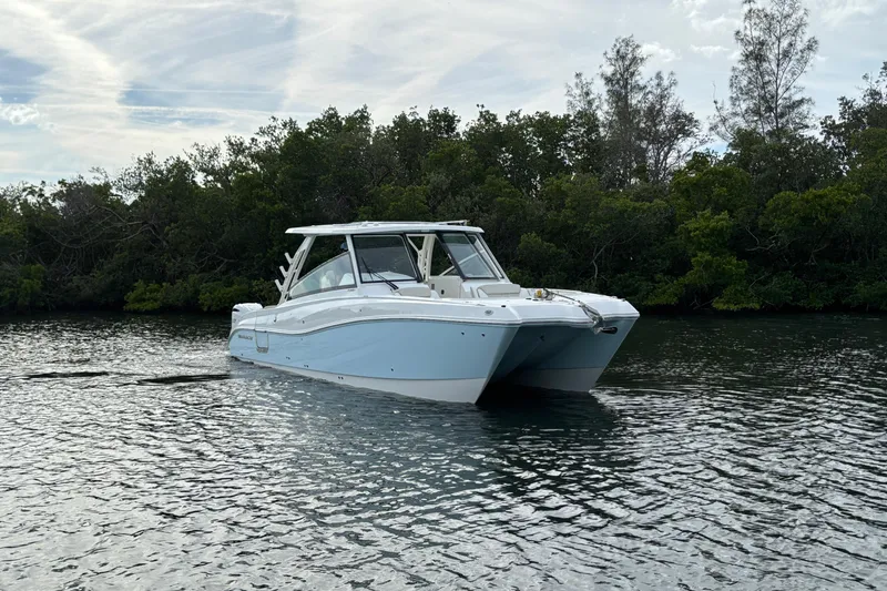 Slide: The Image of 2026 World Cat 325 DC boat cruising on a calm river with lush greenery. - 1
