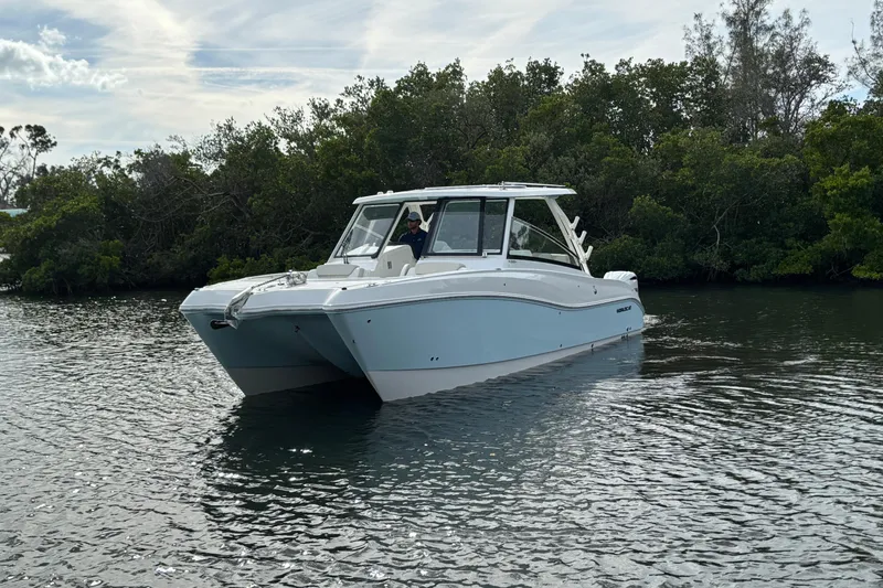 Slide: The Image of 2026 World Cat 325 DC boat cruising on calm water near lush greenery. - 3