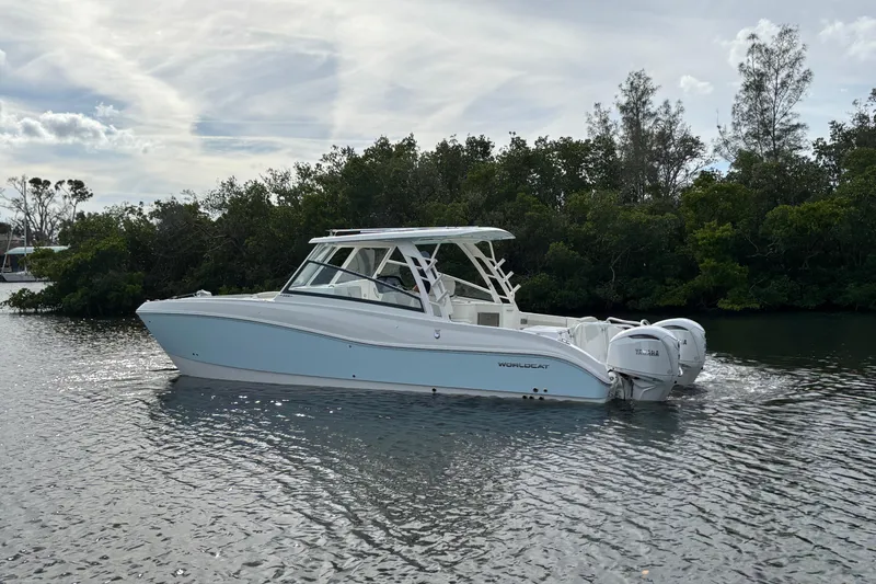 Slide: The Image of 2026 World Cat 325 DC boat cruising on a calm river with lush greenery. - 6