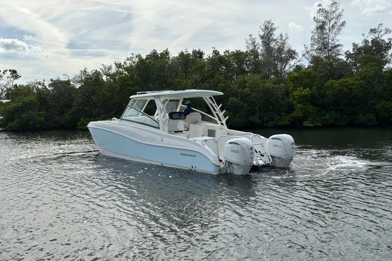 Slide: The Image of 2026 World Cat 325 DC boat cruising on a calm river with lush greenery. - 7