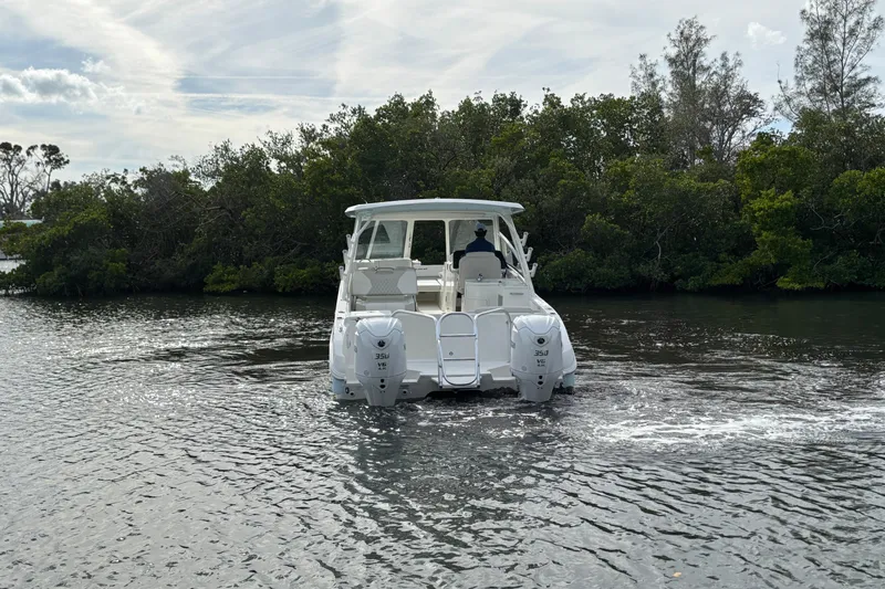 Slide: The Image of 2026 World Cat 325 DC boat cruising on a calm river near lush greenery. - 8
