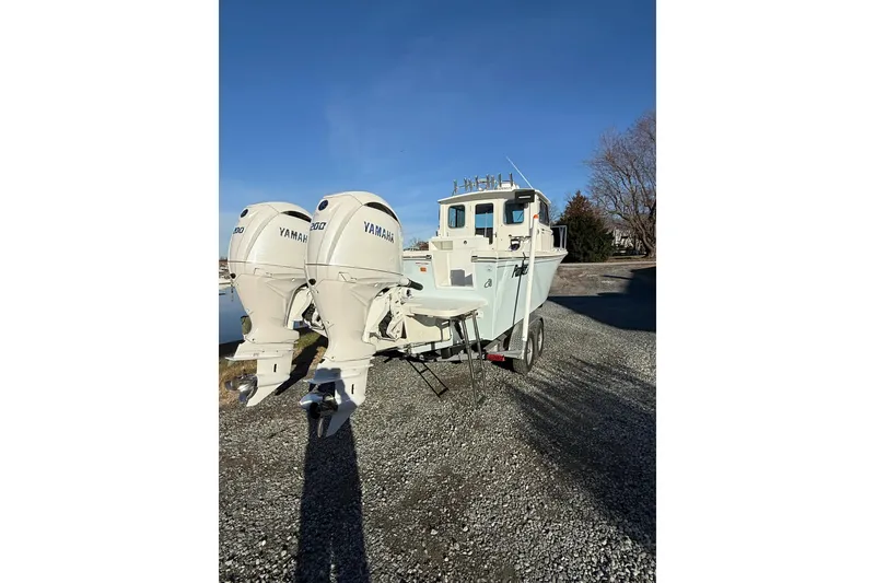 Slide: The Image of 2024 Parker 2520 XLD Sport Cabin boat with dual Yamaha engines on a trailer. - 2