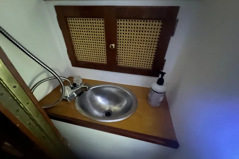 Slide: The Image of Compact sink area on a 1999 Southern Cross Cutter boat with wooden cabinet and soap dispenser. - 10