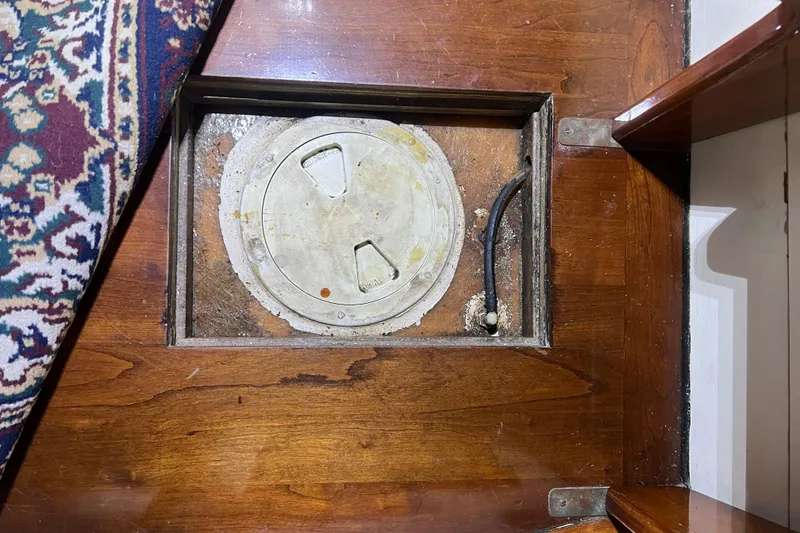 Slide: The Image of Wooden floor hatch on a 1999 Southern Cross Cutter boat, partially covered by a patterned rug. - 11