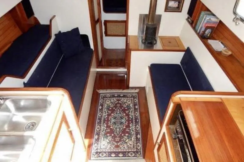 Slide: The Image of Cozy interior of 1999 Southern Cross Cutter with blue seating, wood accents, and a patterned rug. - 2