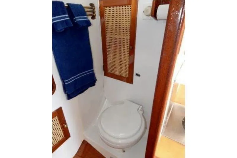 Slide: The Image of Compact bathroom in 1999 Southern Cross Cutter boat with wooden accents and blue towels. - 9