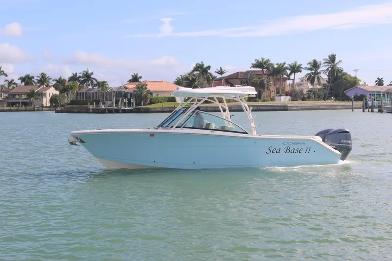 Slide: The Image of 2019 Cobia 280 Dual Console boat cruising on a sunny day near waterfront homes. - 1