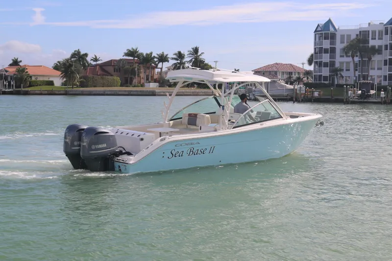 Slide: The Image of 2019 Cobia 280 Dual Console boat on water, featuring twin Yamaha engines. - 11