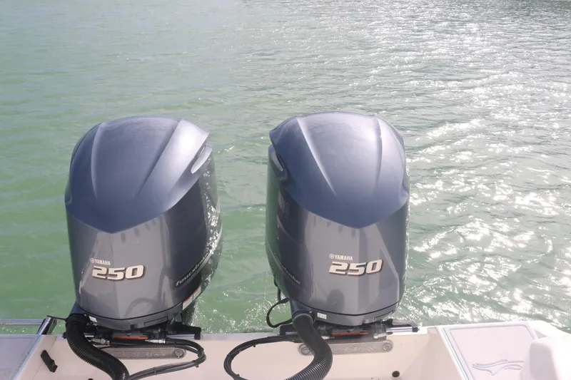 Slide: The Image of 2019 Cobia 280 Dual Console boat interior with table, storage, and twin engines on water. - 16