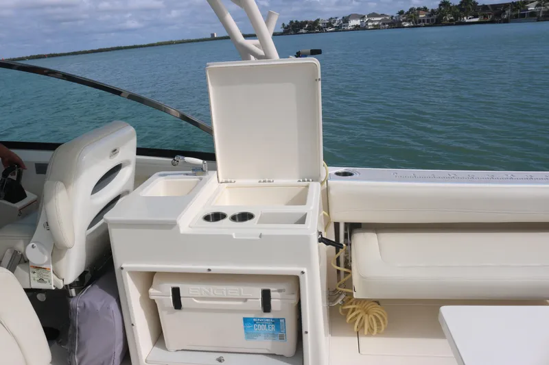 Slide: The Image of 2019 Cobia 280 Dual Console boat interior with seating and storage, under clear blue sky. - 23
