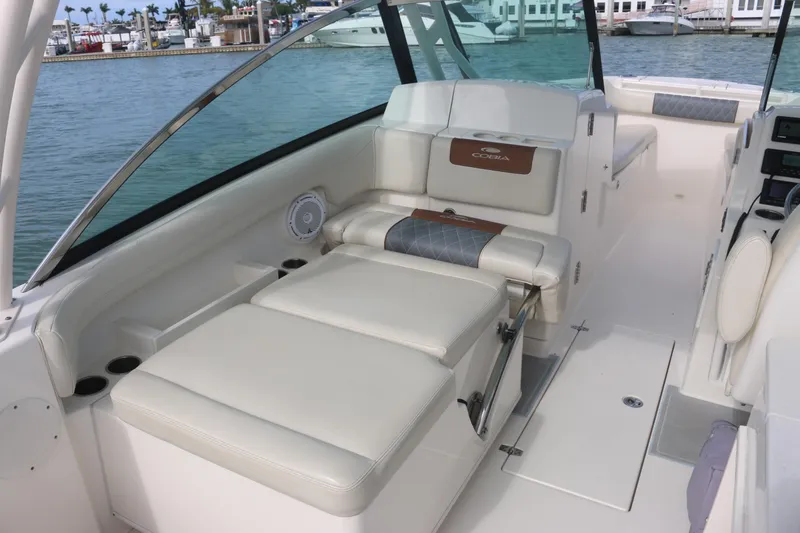Slide: The Image of 2019 Cobia 280 Dual Console boat cockpit with navigation system, steering wheel, and waterfront view. - 26
