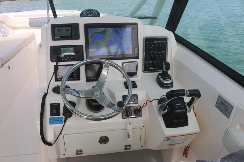 Slide: The Image of 2019 Cobia 280 Dual Console boat helm with navigation equipment and waterfront view. - 27