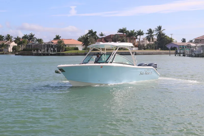 Slide: The Image of 2019 Cobia 280 Dual Console boat cruising on a sunny day near waterfront homes. - 3