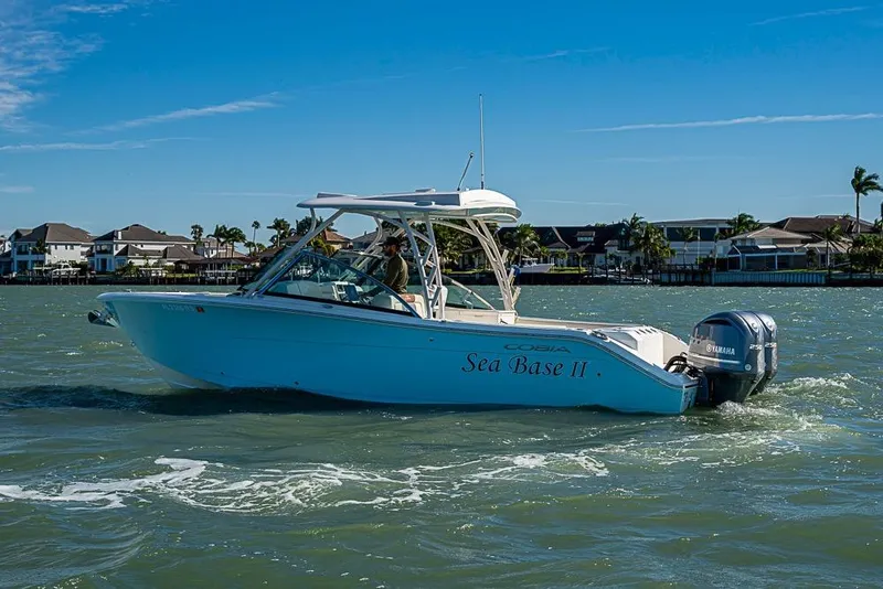 Slide: The Image of 2019 Cobia 280 Dual Console boat cruising on a sunny day near waterfront homes. - 38