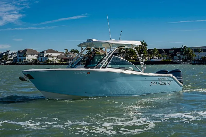 Slide: The Image of 2019 Cobia 280 Dual Console boat cruising on water near waterfront homes. - 40