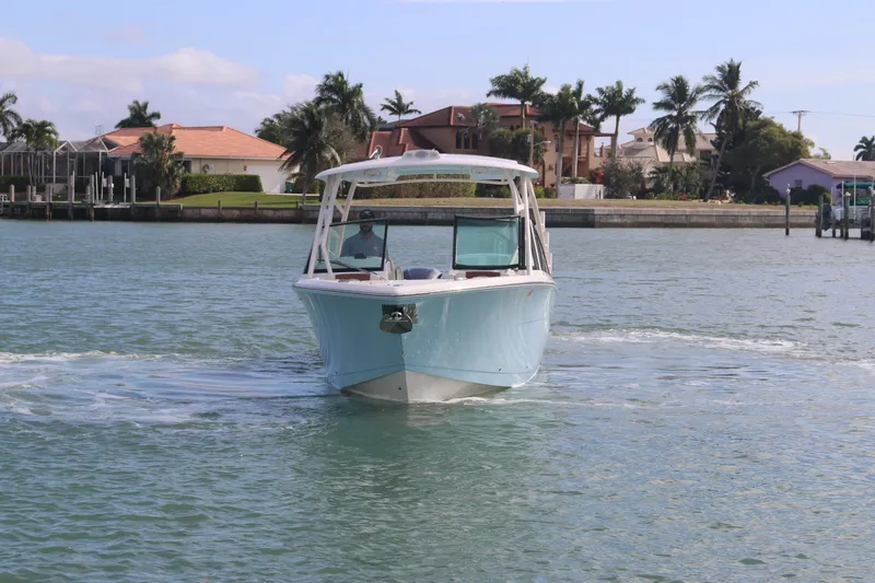 Slide: The Image of 2019 Cobia 280 Dual Console boat cruising on water near waterfront homes. - 6