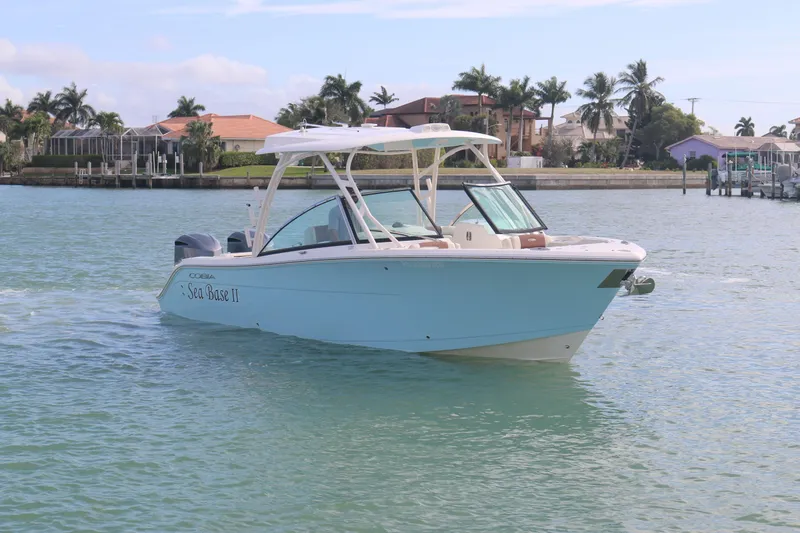 Slide: The Image of 2019 Cobia 280 Dual Console boat cruising on a sunny day near waterfront homes. - 8