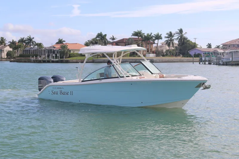 Slide: The Image of 2019 Cobia 280 Dual Console boat cruising on water, clear sky background. - 9