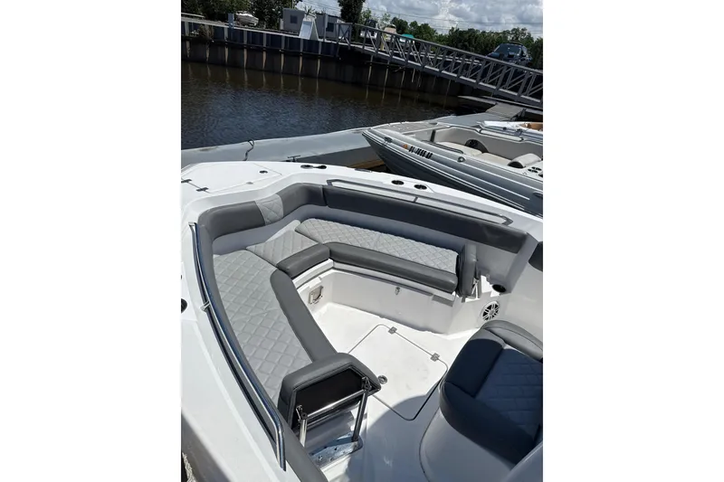 Slide: The Image of 2024 NauticStar 222L Offshore boat with spacious seating, docked by a calm river. - 5