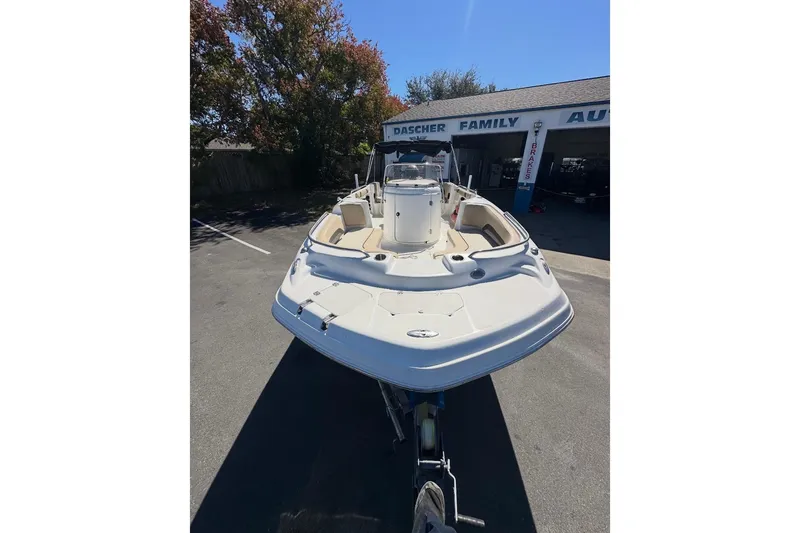 Slide: The Image of 2019 Hurricane SunDeck 237 OB boat in parking lot, front view, near auto shop. - 2