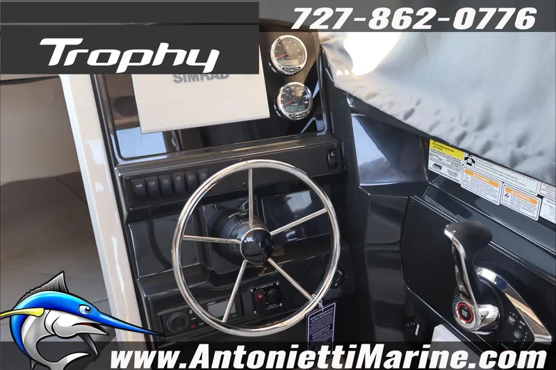 Slide: The Image of 2026 Bayliner Trophy T23 Explorer helm with steering wheel and controls, featuring Simrad electronics. - 25
