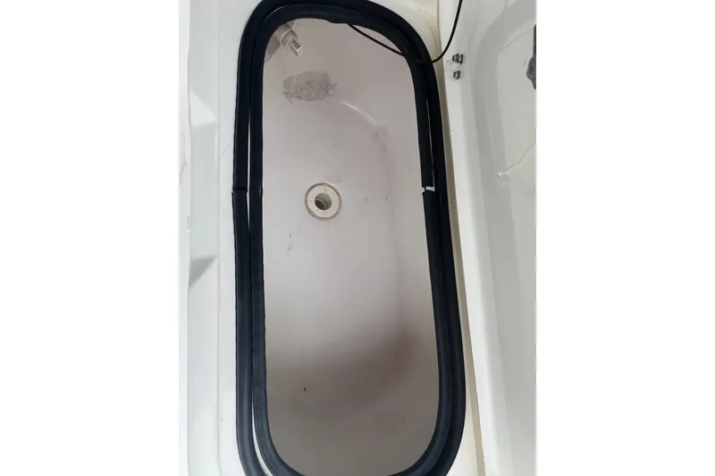 Slide: The Image of Livewell compartment of a 2005 Mako 2101 Inshore boat, featuring a drain plug. - 26
