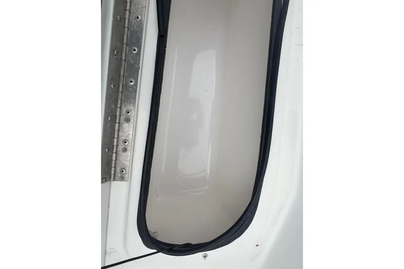 Slide: The Image of 2005 Mako 2101 Inshore boat compartment with metal hinge and rubber seal. - 34