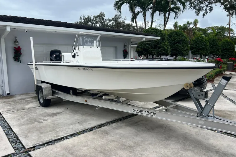 Slide: The Image of 2005 Mako 2101 Inshore boat on trailer in driveway, surrounded by tropical greenery. - 5