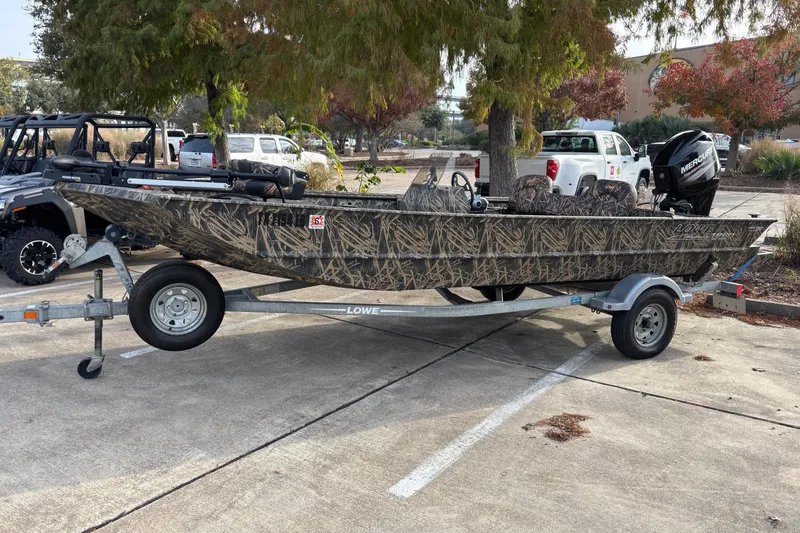 Slide: The Image of 2017 Lowe Roughneck 1860SC boat on trailer, camo design, parked outdoors. - 0
