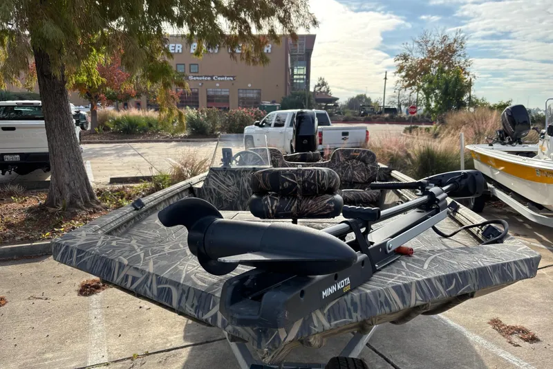Slide: The Image of 2017 Lowe Roughneck 1860SC boat with camo design, parked outdoors near trees. - 2