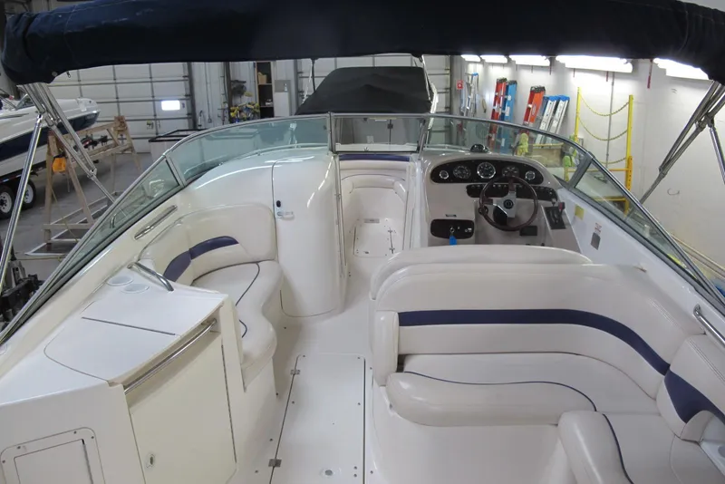 Slide: The Image of 1999 Chaparral 2830 SS boat interior with white seating and steering console in a garage. - 2
