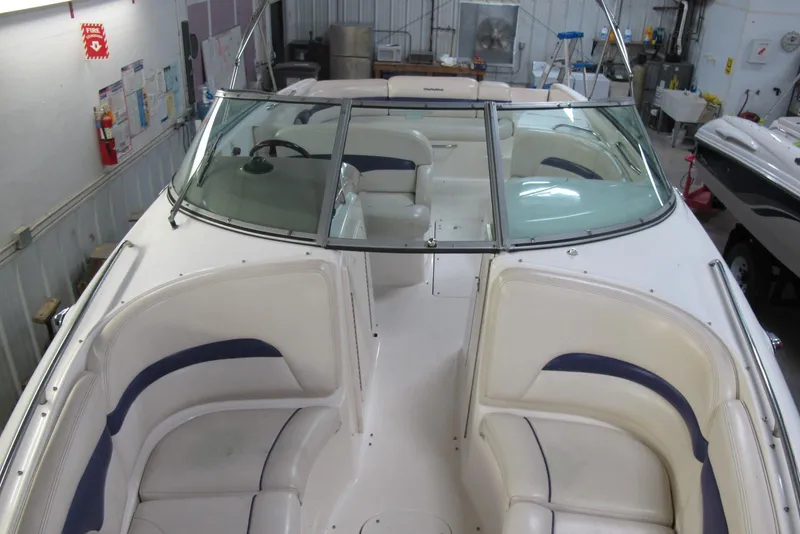Slide: The Image of 1999 Chaparral 2830 SS boat interior with white and blue seating in a garage setting. - 4