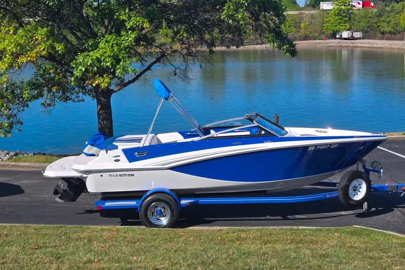 The Image of 2013 Glastron GT 205 boat on trailer by a scenic lake. - 0