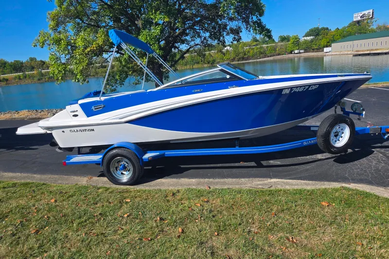 Slide: The Image of 2013 Glastron GT 205 boat on trailer by a lake, under clear blue sky. - 10