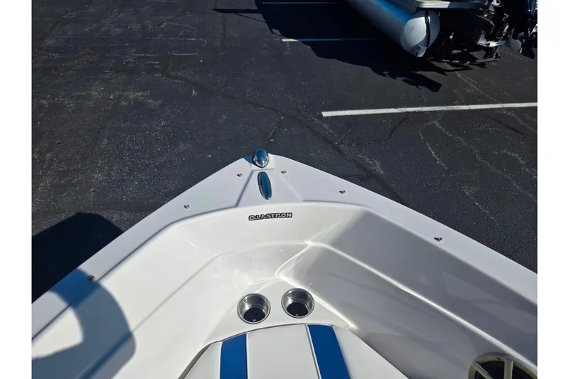 Slide: The Image of 2013 Glastron GT 205 boat bow with blue accents in a parking lot. - 19
