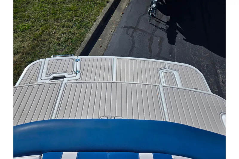 Slide: The Image of 2013 Glastron GT 205 boat deck with blue and white seating, parked on pavement. - 26