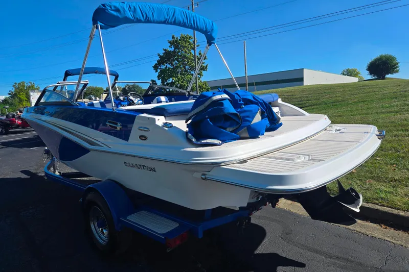 Slide: The Image of 2013 Glastron GT 205 boat with blue canopy on a trailer, parked outdoors. - 3