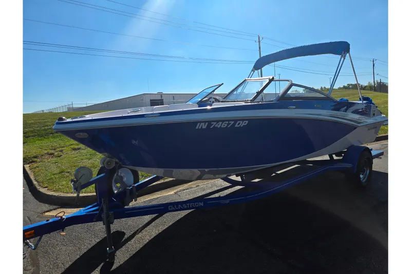 Slide: The Image of 2013 Glastron GT 205 boat on trailer, blue with canopy, parked outdoors. - 5