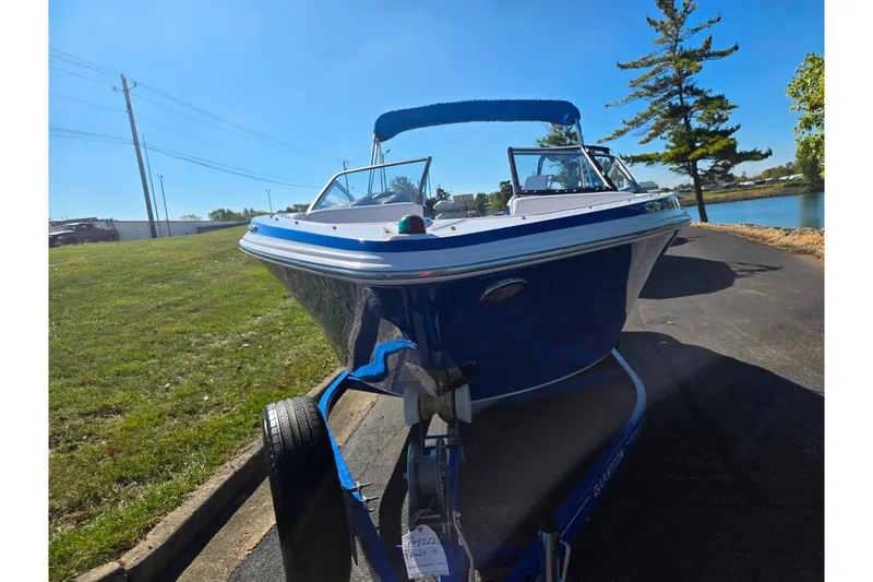 Slide: The Image of 2013 Glastron GT 205 boat on trailer, parked near a lake under clear blue sky. - 6