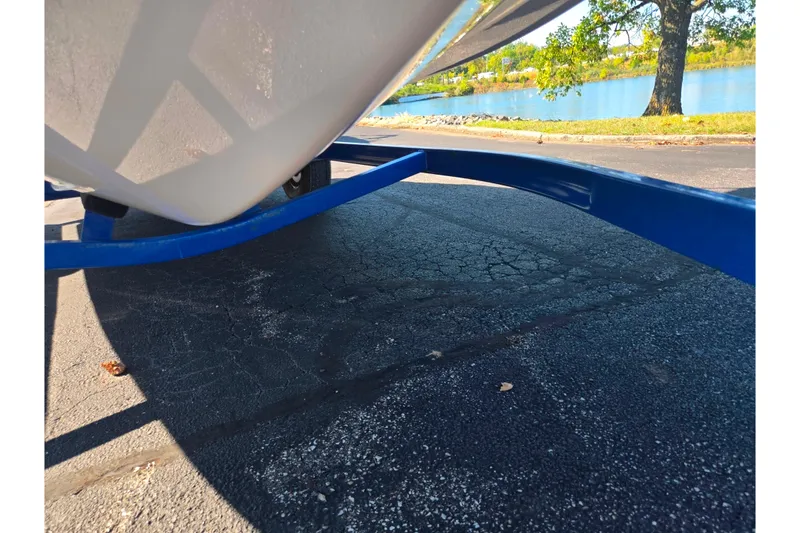 Slide: The Image of 2013 Glastron GT 205 boat on blue trailer near a scenic lake. - 7