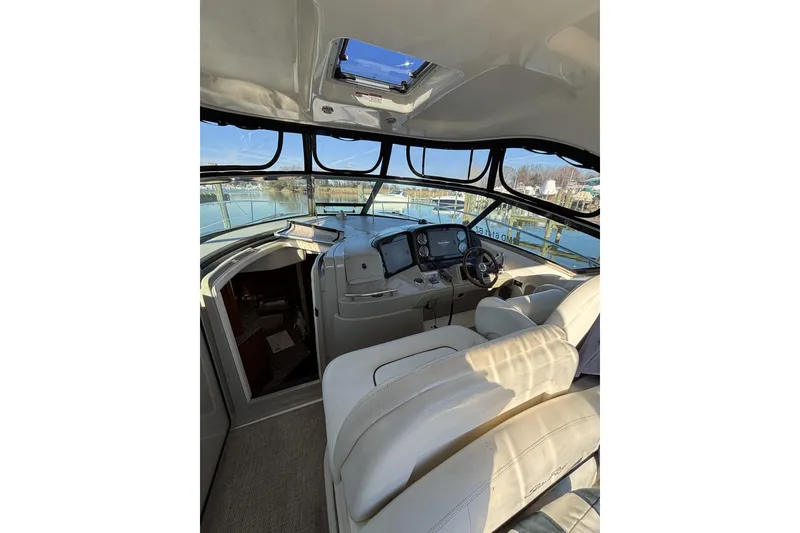 Slide: The Image of 2008 Sea Ray 38 Sundancer cockpit with helm, leather seating, and marina view. - 4