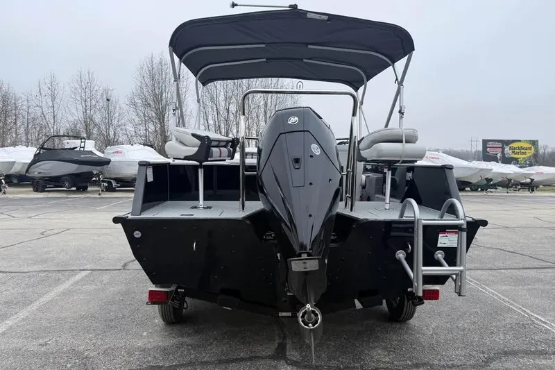Slide: The Image of 2026 Lowe Sport Deck 224 boat with canopy and outboard motor in a parking lot. - 7
