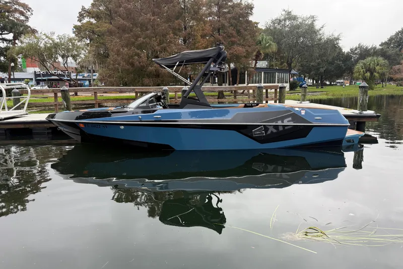 Slide: The Image of 2021 Axis T23 boat docked on calm water, surrounded by trees and a wooden pier. - 11
