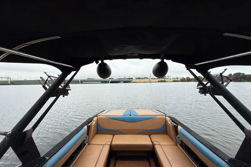 Slide: The Image of Interior view of 2021 Axis T23 boat with tan and blue seating on a calm lake. - 18