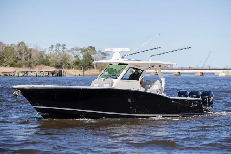 Slide: The Image of 2019 Scout 355 LXF boat cruising on a sunny day with calm waters. - 10